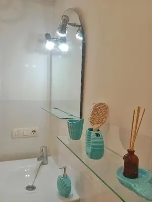 a bathroom with a glass shelf with three vases at Apartamento Fuente de Los Naranjos in Jerez de la Frontera