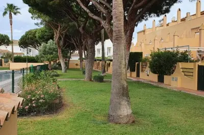 a park with benches and trees and a building at Amplio apart con Wifi y Aire Acondicionado a 500 m de la playa La Barrosa in Chiclana de la Frontera