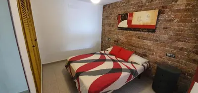 a bedroom with a bed and a brick wall at Amplio apart con Wifi y Aire Acondicionado a 500 m de la playa La Barrosa in Chiclana de la Frontera