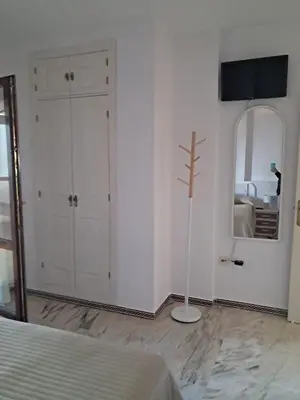 a white bedroom with a mirror and a bed at La caracola in Novo Sancti Petri