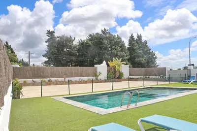 a swimming pool in a yard next to a fence at Apartamento Canario III in Conil de la Frontera
