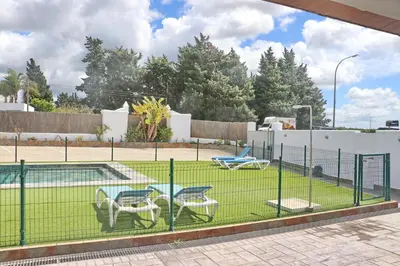 a tennis court with two chairs and a table at Apartamento Canario III in Conil de la Frontera