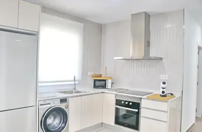 a white kitchen with a washing machine and a microwave at Chalet Ruperto III in Conil de la Frontera