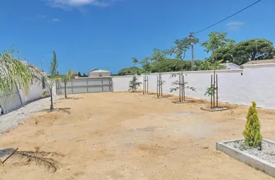 a dirt yard with trees in front of a wall at Chalet Ruperto III in Conil de la Frontera