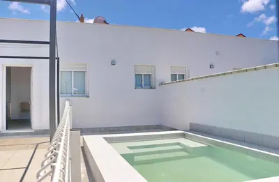 a swimming pool on the side of a white house at Chalet Ruperto II in Conil de la Frontera