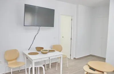 a white table with chairs and a tv on a wall at Chalet Ruperto II in Conil de la Frontera
