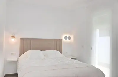 a white bedroom with a large bed with white sheets at Chalet Ruperto II in Conil de la Frontera