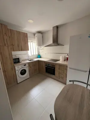a kitchen with a white refrigerator and a table at Apartamento turístico in Chiclana de la Frontera