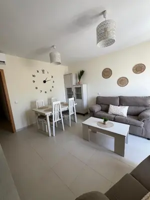 a living room with a couch and a table and a clock at Apartamento turístico in Chiclana de la Frontera