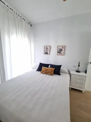 a bedroom with a large white bed with a window at Apartamento de lujo en Playa de Regla in Chipiona