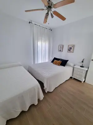 a bedroom with two beds and a ceiling fan at Apartamento de lujo en Playa de Regla in Chipiona