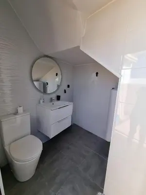 a white bathroom with a toilet and a mirror at Apartamento de lujo en Playa de Regla in Chipiona