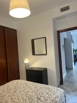 a bedroom with a bed and a table and a mirror at Apartamento Edificio Carruaje in Jerez de la Frontera