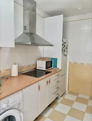 a kitchen with a stove top oven next to a microwave at Playa Fuentebravia apartament in El Puerto de Santa María