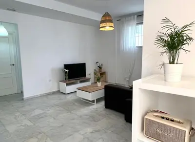 a living room with a television and a living room with a couch at Playa Fuentebravia apartament in El Puerto de Santa María