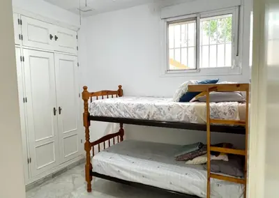 a bedroom with two bunk beds and a window at Playa Fuentebravia apartament in El Puerto de Santa María