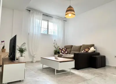 a living room with a couch and a tv at Playa Fuentebravia apartament in El Puerto de Santa María