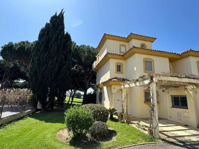 a large yellow house with a grass yard at Chalet adosado en Novo Sancti Petri in Cádiz