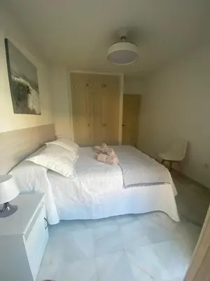 a bedroom with a large white bed with a lamp at Apartamento Capillera 9 in El Puerto de Santa María