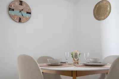 a table with chairs and a clock on the wall at Rinconcito Sanlucar de Barrameda in Sanlúcar de Barrameda