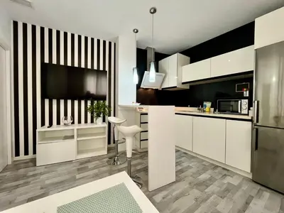 a kitchen with white cabinets and a flat screen tv at GATU Alquiladores 
