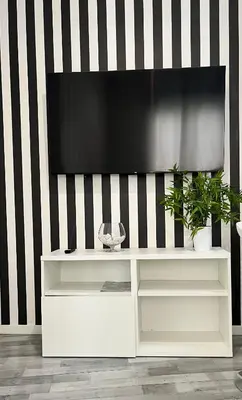 a white entertainment center with a television on a striped wall at GATU Alquiladores 