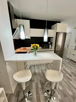 a kitchen with a white counter and two stools at GATU Alquiladores 