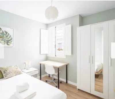 a white bedroom with a desk and a bed at Alma gaditana en la caleta in Cádiz