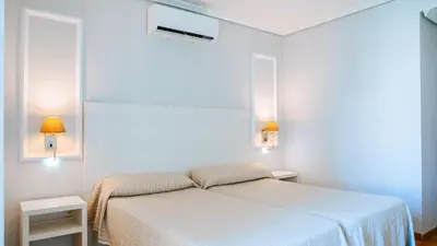 a white bedroom with a bed and two tables at Bungalows Bahia Sur in San Fernando