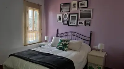 a bedroom with a bed with a purple wall at Ático Mar in Sanlúcar de Barrameda