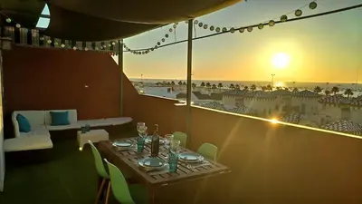 a table with a view of the beach at sunset at Ático Mar in Sanlúcar de Barrameda