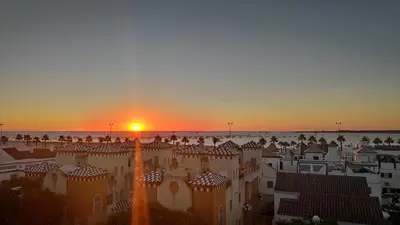 a sunset over the roofs of buildings in a city at Ático Mar in Sanlúcar de Barrameda