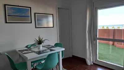 a white table and green chairs in a room with a window at Ático Mar in Sanlúcar de Barrameda