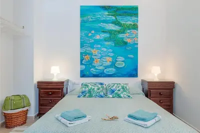 a bedroom with a bed with a painting on the wall at Alojamientos Cadiz Sol in Cádiz