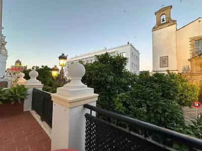a street with a fence and a building with a clock tower at Sherryflat Terraza San Francisco in Jerez de la Frontera