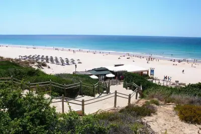 a beach with umbrellas and a crowd of people at Casa doble Almadraba in Novo Sancti Petri