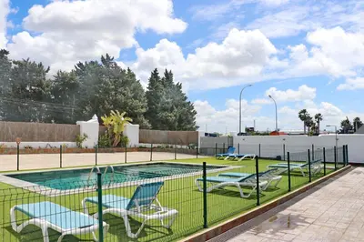 a swimming pool with chairs and a fence at Apartamento Canario IV in Conil de la Frontera