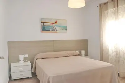 a bedroom with a bed and a painting on the wall at Apartamento Canario IV in Conil de la Frontera