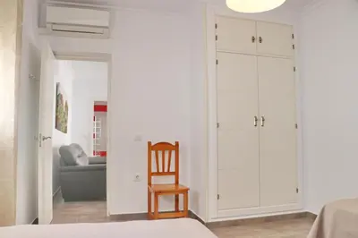 a bedroom with white cabinets and a wooden chair at Apartamento Canario IV in Conil de la Frontera