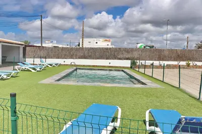 a swimming pool with chairs and a fence at Apartamento Canario IV in Conil de la Frontera