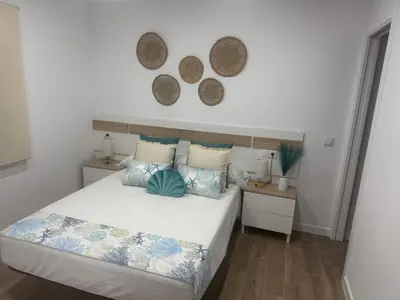 a bedroom with a bed with two tables and two mirrors at Apartamento Bajo De Guía - Bajo A in Sanlúcar de Barrameda