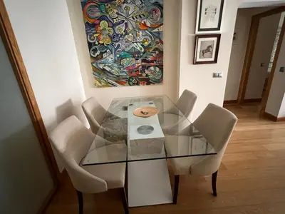 a glass table with chairs and a painting on the wall at Apartamento Jerez in Jerez de la Frontera