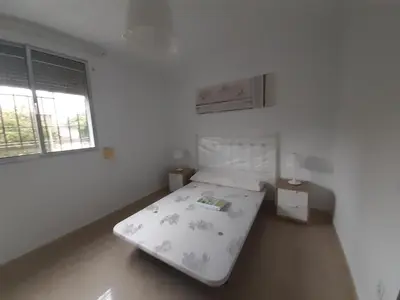 a white bedroom with a bed and two windows at Granadina 4 in Jerez de la Frontera