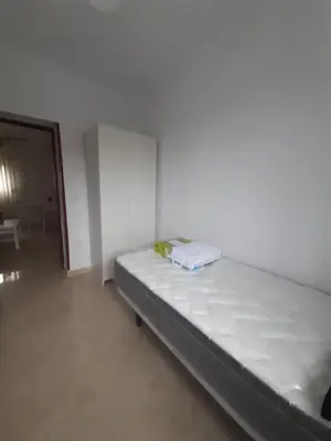a bed in a room with a white wall at Granadina 4 in Jerez de la Frontera