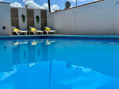 a swimming pool with blue water and yellow chairs at GATU Villa Serena piscina privada mayores de 25 años y familias in Chiclana de la Frontera