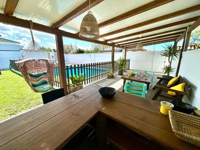 a patio with a wooden table and a hammock at GATU Villa Serena piscina privada mayores de 25 años y familias in Chiclana de la Frontera