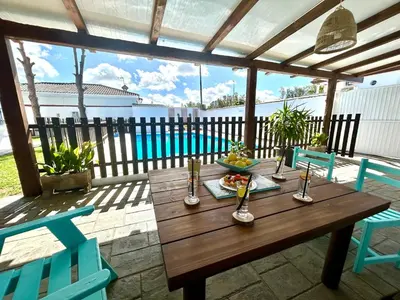 a wooden table on a patio with two blue chairs at GATU Villa Serena piscina privada mayores de 25 años y familias in Chiclana de la Frontera