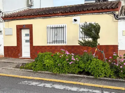 a red brick house with a white door and some flowers at Casita de Don Juan Tenorio in Torrecera