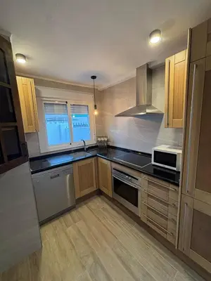 a kitchen with stainless steel appliances and wooden cabinets at Casita de Don Juan Tenorio in Torrecera