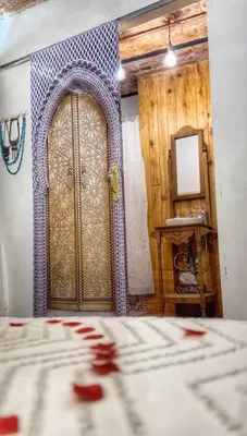 a bedroom with a large wooden door and a mirror at Casa arabe in Alcalá de los Gazules